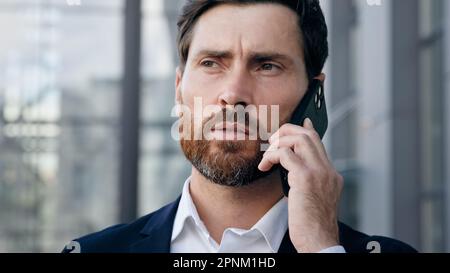 Portrait serious confident businessman talking on phone answering business call professional manager communicates with client using mobile connection Stock Photo