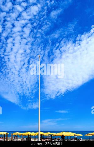 Malaga Benalmadena beach early morning with straw topped  beach huts and sunbathers against an unusual cloud formation   and deep blue sky Stock Photo