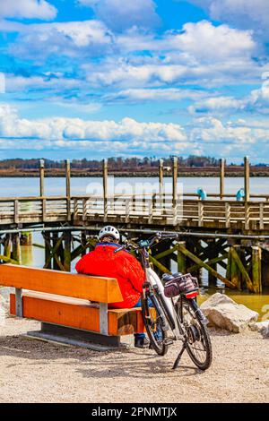 Older gentleman with his battery assist bike resting on the bank of the Fraser River in Vancouver Canada Stock Photo