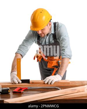 Male carpenter measuring wooden plank at table on white background Stock Photo