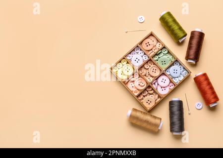 Composition with different buttons, thread spools and ball pins on color background Stock Photo