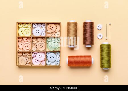 Composition with different buttons and thread spools on color background Stock Photo