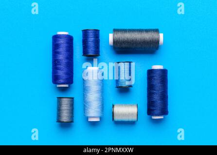 Composition with different thread spools on color background Stock Photo