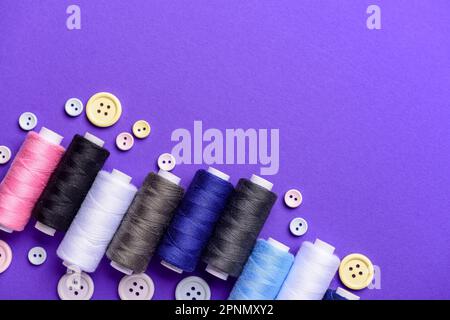 Composition with different thread spools and buttons on color background Stock Photo