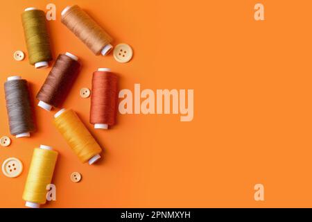 Composition with different thread spools and buttons on color background Stock Photo