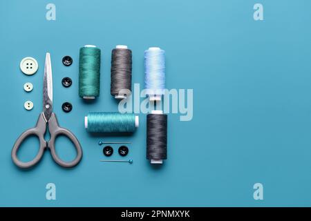 Composition with thread spools, buttons and scissors on color background Stock Photo