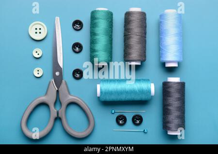 Composition with thread spools, buttons, scissors and ball pins on color background Stock Photo