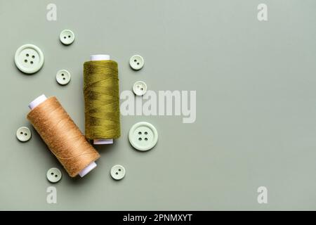 Composition with thread spools and buttons on grey background Stock Photo