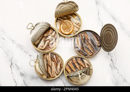 Opened tin cans with sprats in oil on white marble table Stock Photo
