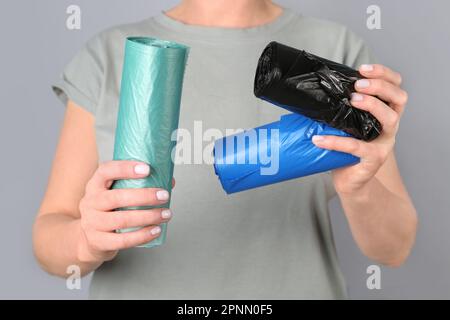 Woman holding rolls of garbage bags on grey background Stock Photo