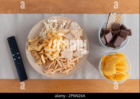 Top view of snack on wooden table and remote control Stock Photo