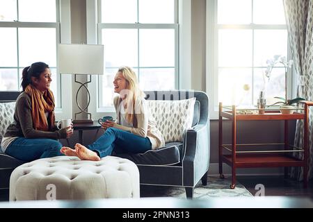 Nothing she values more than a visit from her friend. two young women having coffee together on a relaxing day at home. Stock Photo