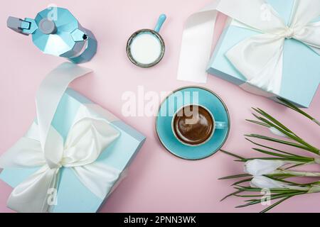 A cup of coffee and a gift box with a white bow on a pink background.  Stock Photo