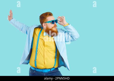 Cool bearded fat man in colorful stylish clothes and sunglasses is having fun and enjoying disco. Stock Photo