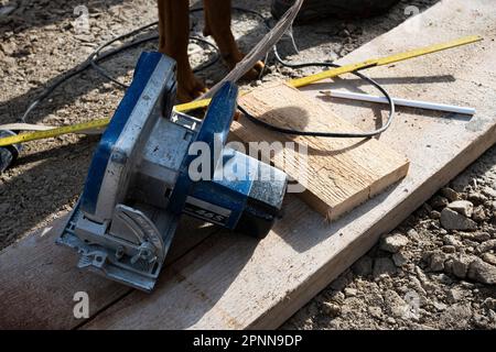 A close-up image of a table saw cutting through a piece of wood on a wooden workbench Stock Photo