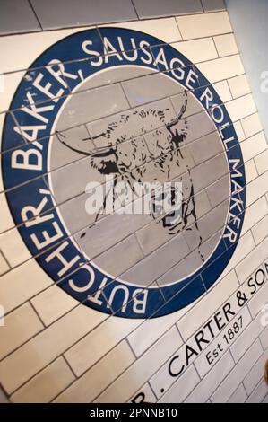 Tiled logo on wall in R Carter and Son, Butchers shop in Bamburgh, Northumberland Stock Photo