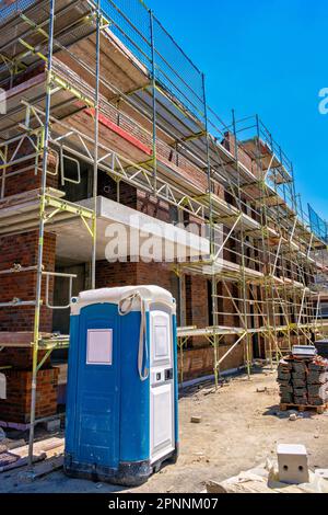 Scaffolding and a blue bio-toilet near a high-rise brick house under construction in Germany. Stock Photo