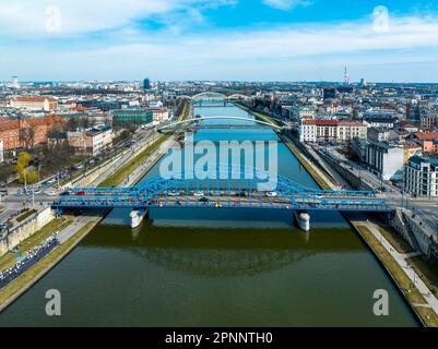 Bridges on Vistula River in Krakow, Poland. Aerial view. Boulevards with waking people. Blue tied-arc bridge in front. Footbridge for pedestrians and Stock Photo