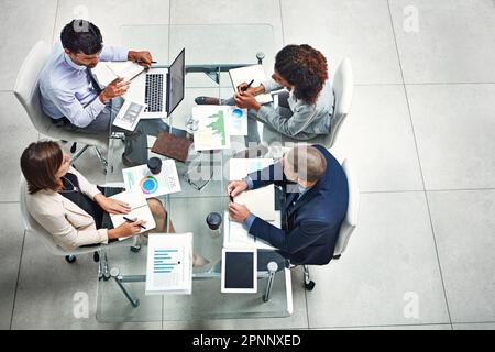 Laying the facts and figures out on the table. High angle shot of a group of colleagues working together on a project in a modern office. Stock Photo