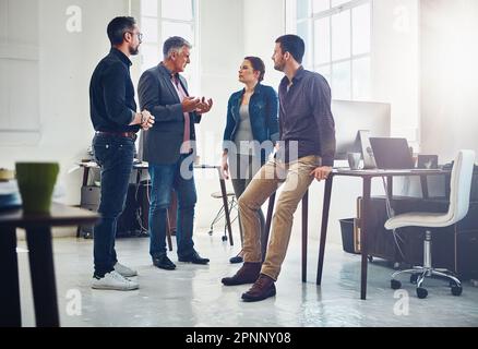 Keeping their brilliance on target. a group of designers having a discussion at work. Stock Photo