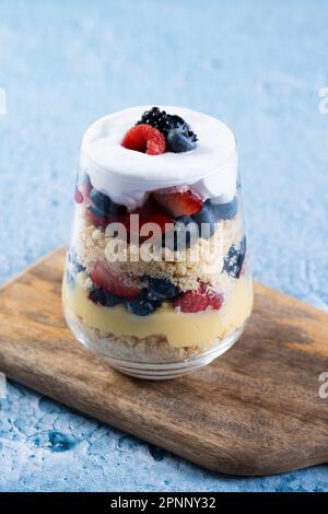 Trifle dessert with berries and cream on blue background Stock Photo