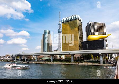 Sumida River Toky0. river boat passes Tokyo Sky Tree worlds tallest tower and Asahi flame, beer hall and offices, April 2023,Japan,Asia Stock Photo