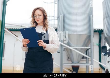 Woman Agricultural Engineer with Documents Near Cyclone Industrial Equipment. Stock Photo