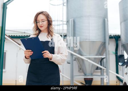 Woman Agricultural Engineer with Documents Near Cyclone Industrial Equipment. Stock Photo