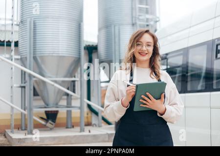 Woman Agricultural Engineer with Tablet Near Cyclone Industrial Equipment Stock Photo