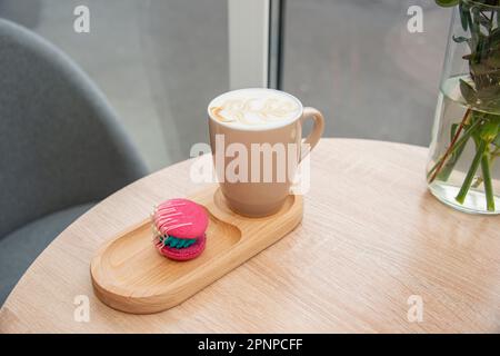 cup of coffee latte and colorful pink macaroons on wooden table Stock Photo