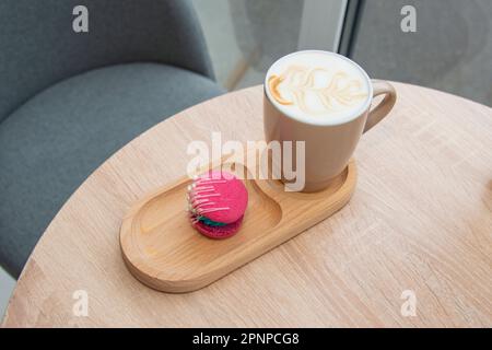 cup of coffee latte and colorful pink macaroons on wooden table Stock Photo