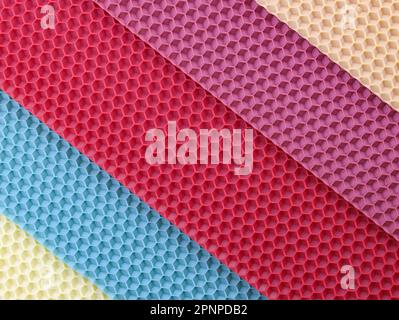 Sheets in the form of honeycombs from wax for making candles red, pink, beige. Set of colored beeswax sheets top view. Hobby wax candles. Stock Photo