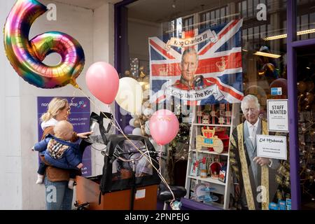 With two weeks before the coronation of King Charles III takes place, a mother attaches party balloons into her cargo bike  after buying them from a party and balloon business selling royal merchandise, on 19th April 2023, in London, England. King Charles will succeed Queen Elizabeth II on 6th May, who passed away last year. Stock Photo