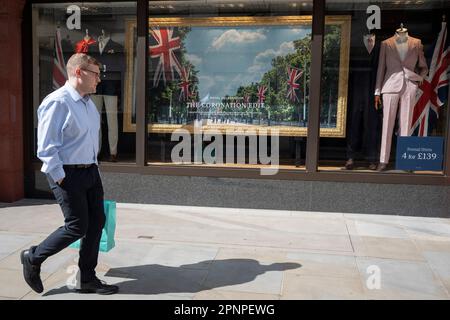 With two weeks before the coronation of King Charles III takes place, A man walks past a menswear clothing retailer featuring a Mall and union jack flags coronation theme, on Jermyn Street, on 19th April 2023, in London, England. King Charles will succeed Queen Elizabeth II on 6th May, who passed away last year. Stock Photo