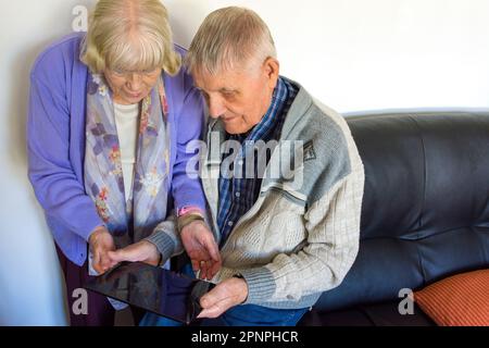 Senior elderly couple using a tablet computer with wifi broadband connection. Stock Photo