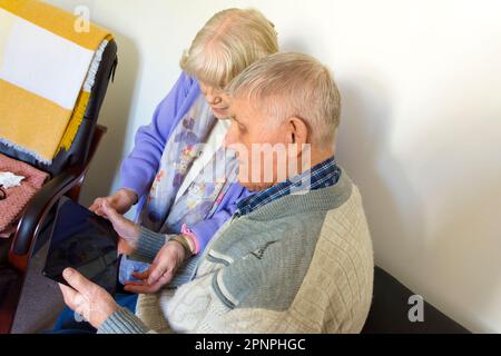 Senior elderly couple using a tablet computer with wifi broadband connection. Stock Photo