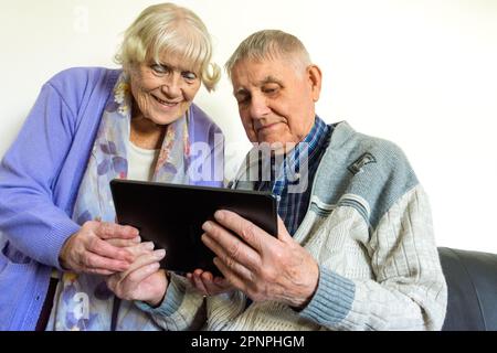 Senior elderly couple using a tablet computer with wifi broadband connection. Stock Photo