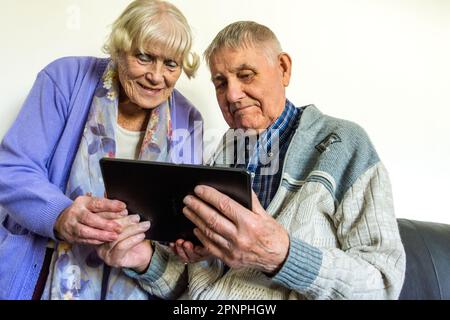 Senior elderly couple using a tablet computer with wifi broadband connection. Stock Photo