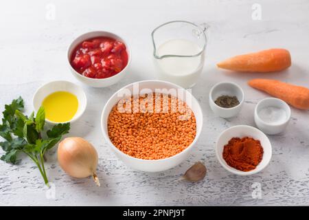 Ingredients for creamy lentil soup: red lentils, onion, carrot, garlic, tomato passata, cream, olive oil, smoked paprika, salt, pepper, herbs on a lig Stock Photo