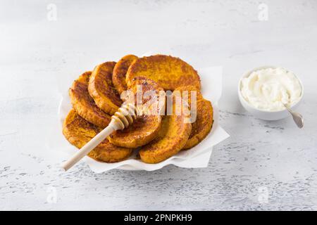 Sweet pumpkin toast with honey and cream, sprinkled with powdered sugaron a light blue textured background, top view. Delicious homemade breakfast Stock Photo