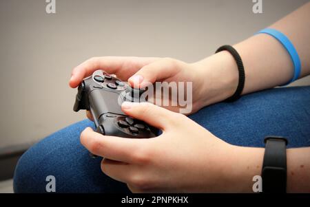 A close-up shot of hands holding a video game controller and playing Stock Photo
