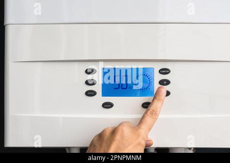 Hand adjust gas boiler control panel for comfort home heating and hot water. Concept of energy saving and heat conservation Stock Photo