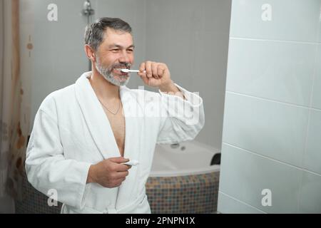 Smiling male brushing teeth in the hostel Stock Photo