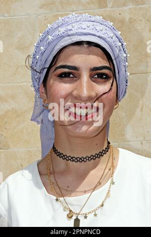 A Yazidi woman in colorful clothes is seen participating in the celebration of the Red Wednesday holiday in the Bacinê village. Yazidi Kurds living in the Bacine village of Midyat district and Besiri districts in Turkey celebrated the Red Wednesday holiday, known as 'Charshema Sor' in Kurdish, joyfully with various entertainments. Men, women and children of 10 Yazidi families living in the village of Bacine gathered at the Yazidi Cultural Center after morning prayers, wearing the most colorful and beautiful dresses. Yazidis believe that April is a holy spring month and that the world was creat Stock Photo