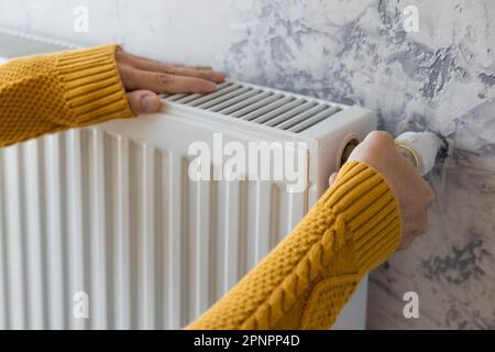 Man adjusting heating radiator or heater to install comfort temperature for energy efficiency and economy in winter. Concept of heating season Stock Photo