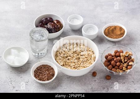 Ingredients for cooking healthy oatmeal cookies: oatmeal, flaxseed, nuts (hazelnuts and walnuts), coconut oil, water, dates, coconut sugar, salt and b Stock Photo