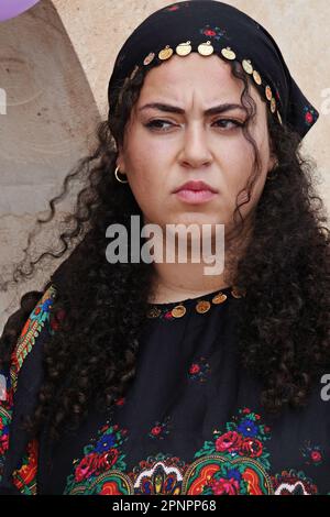 A Yazidi woman wearing colorful clothes participates in the celebration of the Red Wednesday holiday in the Bacinê village. Yazidi Kurds living in the Bacine village of Midyat district and Besiri districts in Turkey celebrated the Red Wednesday holiday, known as 'Charshema Sor' in Kurdish, joyfully with various entertainments. Men, women and children of 10 Yazidi families living in the village of Bacine gathered at the Yazidi Cultural Center after morning prayers, wearing the most colorful and beautiful dresses. Yazidis believe that April is a holy spring month and that the world was created i Stock Photo