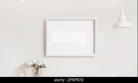 White wooden frame for pictures with rectangular horizontal shape on white wall with decoration lamp and flower mockup template Stock Photo