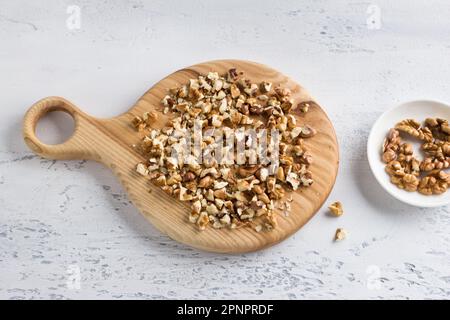 Wooden board with chopped walnut on light blue background, top view Stock Photo