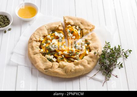 Homemade galette with pumpkin, feta cheese, honey, pumpkin seeds and thyme on white background, top view Stock Photo